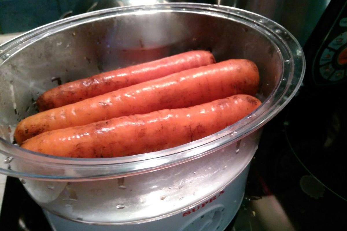raw carrots immersed in a double boiler